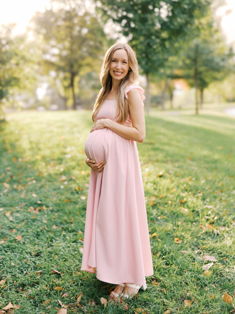 what to wear for maternity photos - woman in pink dress holding belly
