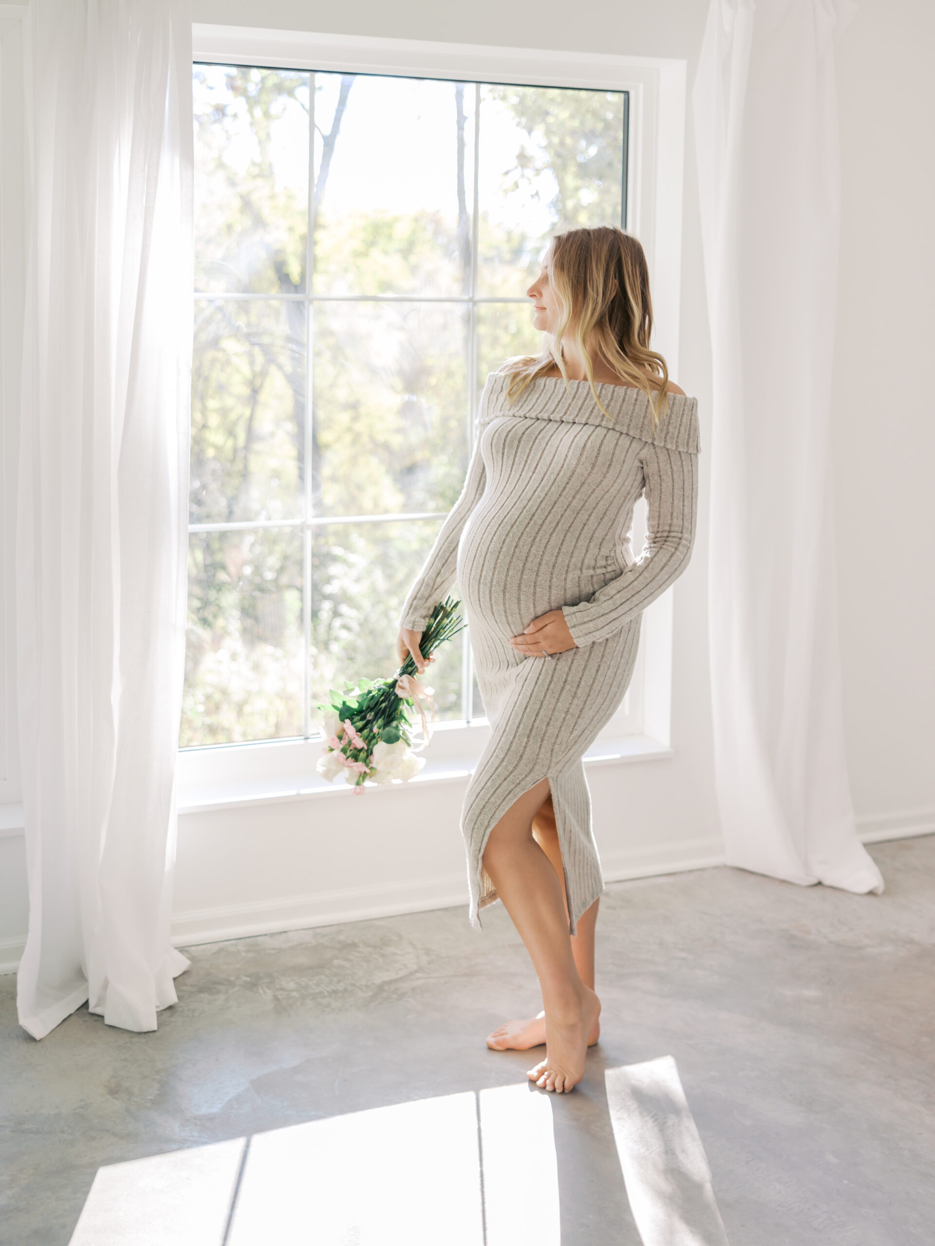 Woman poses in an elegant, light filled studio setting for her minneapolis maternity photography session with angela watts photography