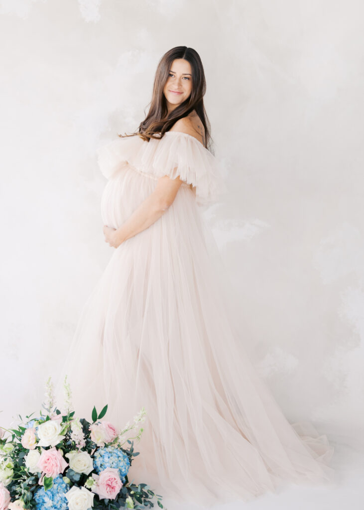 what to wear for maternity photoshoot - woman in pink tulle maternity gown in a minneapolis studio