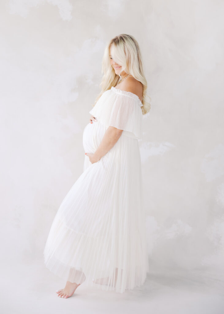 what to wear for maternity photos - woman in white tulle off the shoulder maternity gown in minneapolis