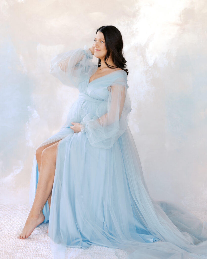 woman in blue tulle maternity gown poses in a studio setting for her minneapolis maternity photos
