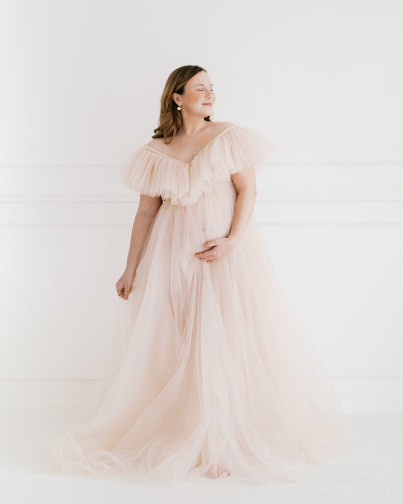 elegant image of woman in blush pink tulle maternity gown in a studio setting during her minneapolis maternity photography session