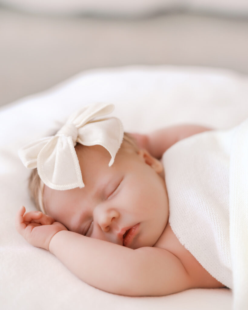 Newborn baby sleeps on white blanket during her studio newborn session with minneapolis newborn photographer, Angela Watts