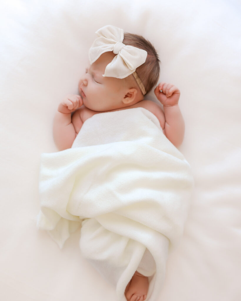 Newborn baby sleeps on white blanket during her studio newborn session with minneapolis newborn photographer, Angela Watts