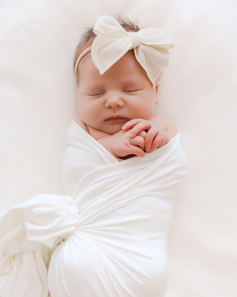 Newborn baby sleeps on white blanket during her studio newborn session with minneapolis newborn photographer, Angela Watts