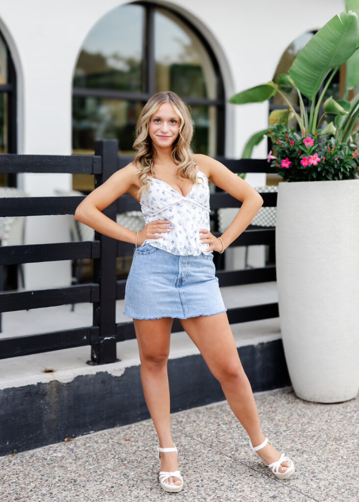 Girl in white tank and denim skirt poses downtown Wayzata for her wayzata senior pictures with angela watts photography