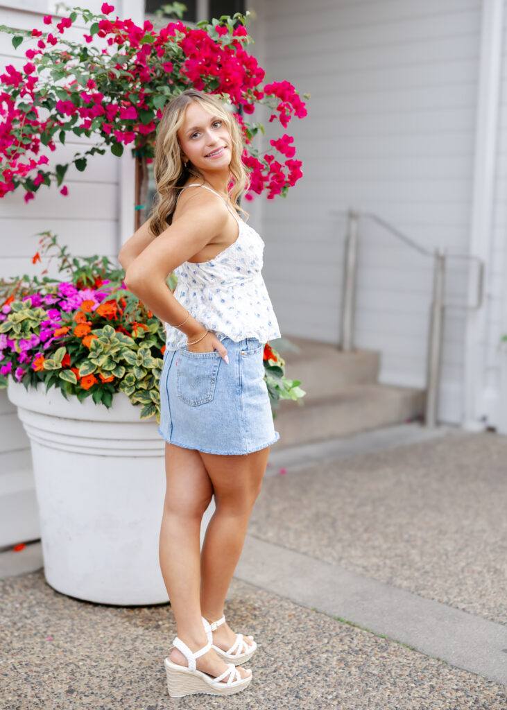 girl in denim skirt and cute top poses downtown wayzata for her minneapolis senior photos with angela watts photography