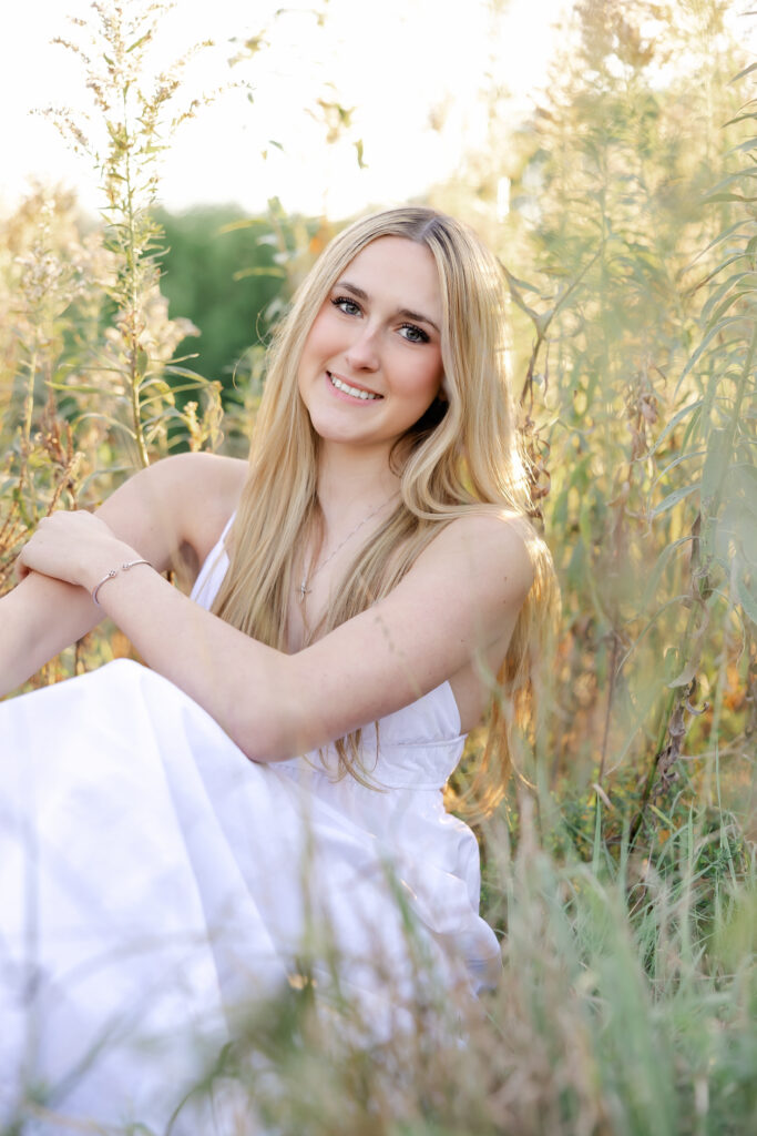 girl in long white dress poses at golden hour for her wayzata senior portraits