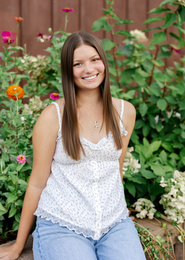 girl in white tank and jeans poses downtown excelsior, mn for her eden prairie senior pictures