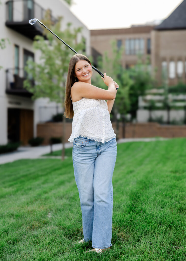 girl swings a golf club downtown excelsior, mn for her eden prairie senior pictures