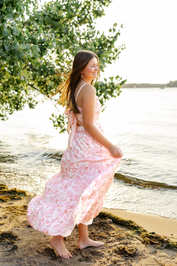 girl in pink dress poses at excelsior beach for her minneapolis senior photos with angela watts photography