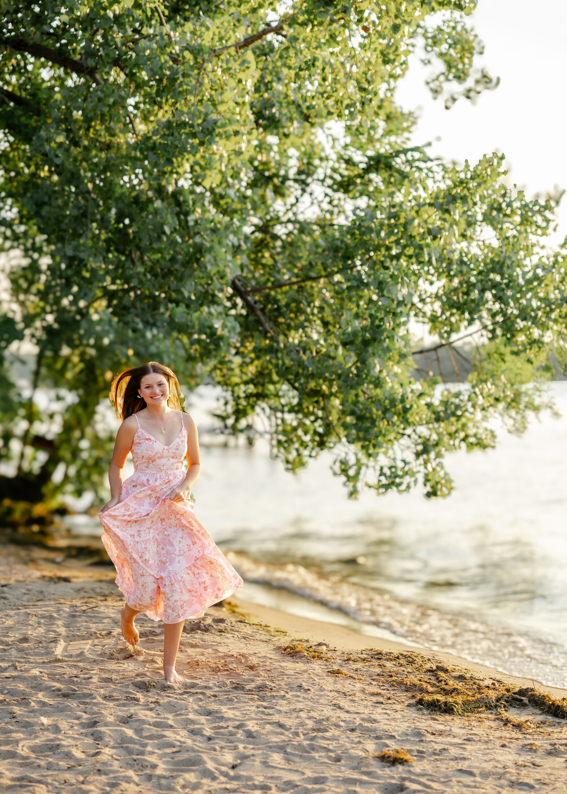 Girl runs along Excelsior beach in white and pink flowy dress for her eden prairie senior pictures with senior photographer angela watts photography.