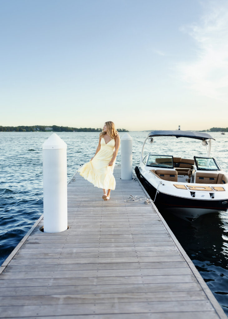 girl in yellow dress poses at wayzata docks for her minneapolis senior photos with angela watts photography