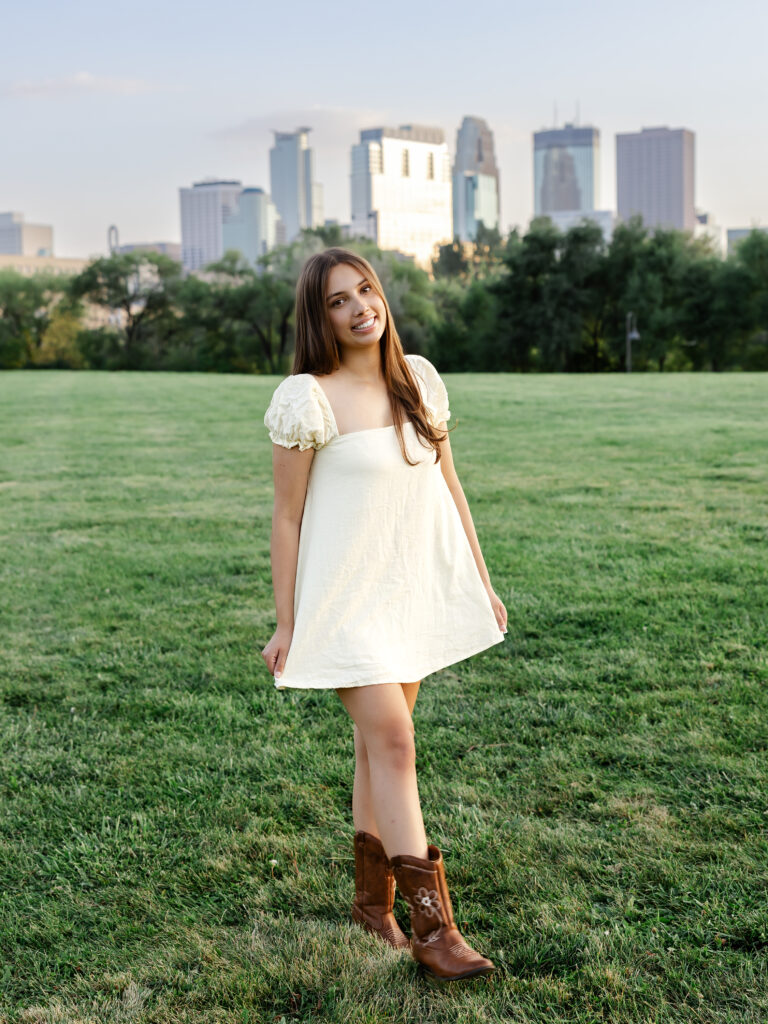 girl in pink dress poses at boom island park for her minneapolis senior photos with angela watts photography