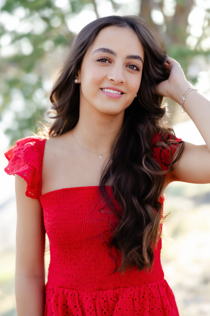 girl in red dress smiles at lake harriet for her minneapolis senior portraits