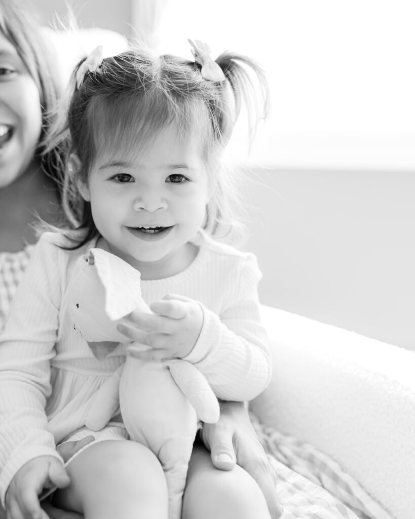 2 year old girl snuggles with family in their edina, mn home for their in-home newborn photography session with angela watts.