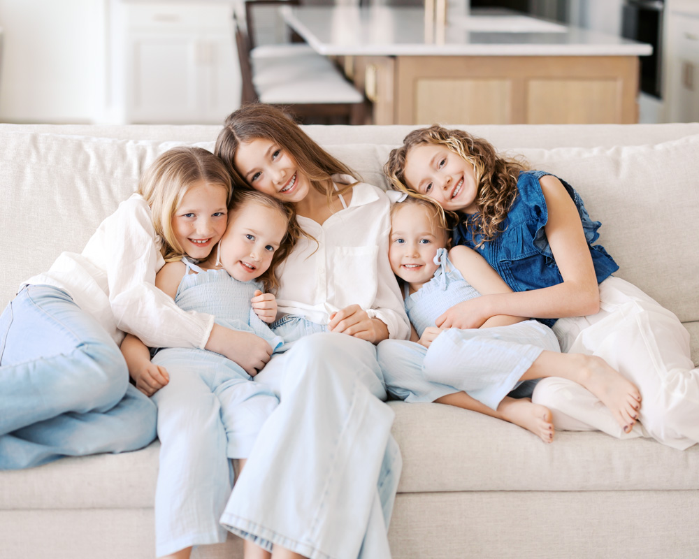 5 sibling girls sit on a sofa in their minneapolis home during their family photography session