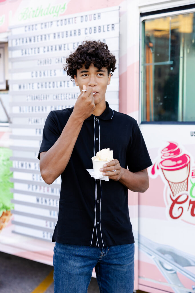 boy is eating ice cream near an ice cream truck at mill ruins park, minneapolis for his minnetonka senior pictures