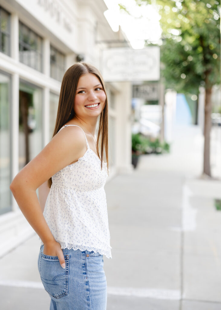 girls in white tank and jeans walks downtown excelsior, mn for her eden prairie senior pictures
