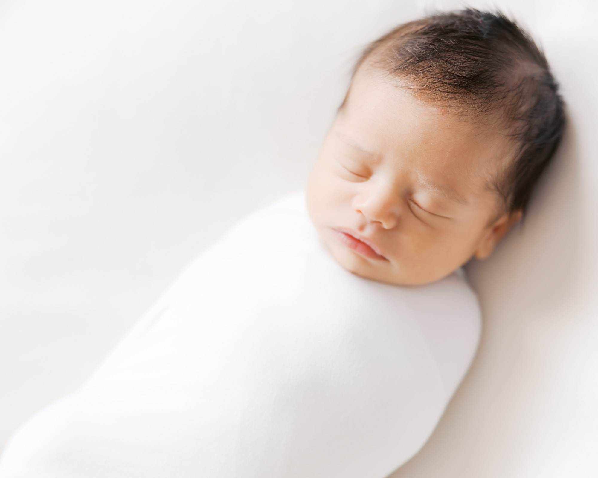 newborn baby boy swaddled up sleeps on a beanbag during his minneapolis newborn photography session.