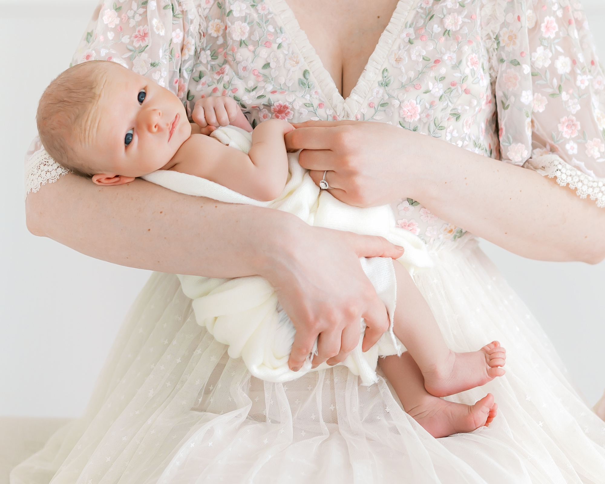 baby boy in moms arms looks at the camera during his minneapolis newborn photography session