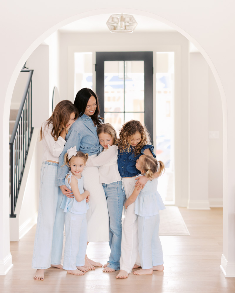 Mom snuggles 5 daughters in their edina home entryway for their edina family photography session