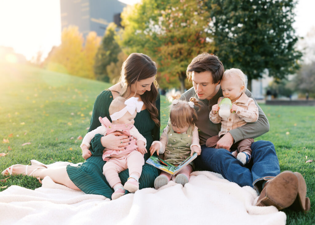 Family of 5 sit on a blanket at gold medal park in minneapolis, minnesota for their family photography session with angela watts photography