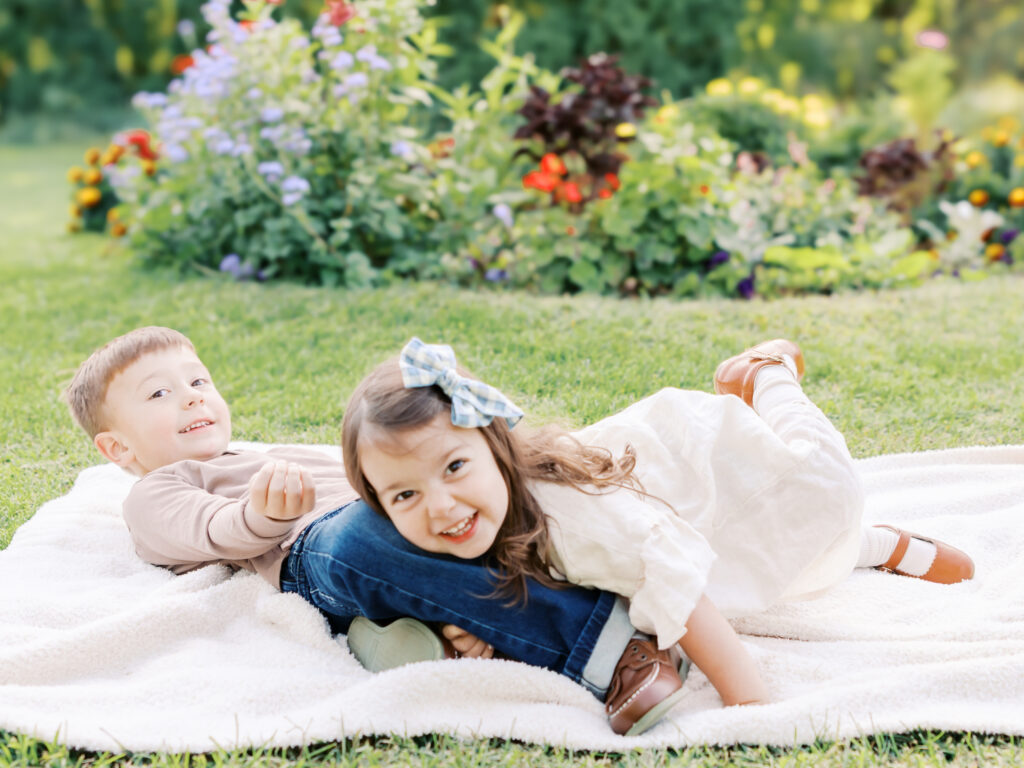 two young boy/girl siblings wrestle on a blanket at arneson acres park in edina, mn for their minneapolis family photography session