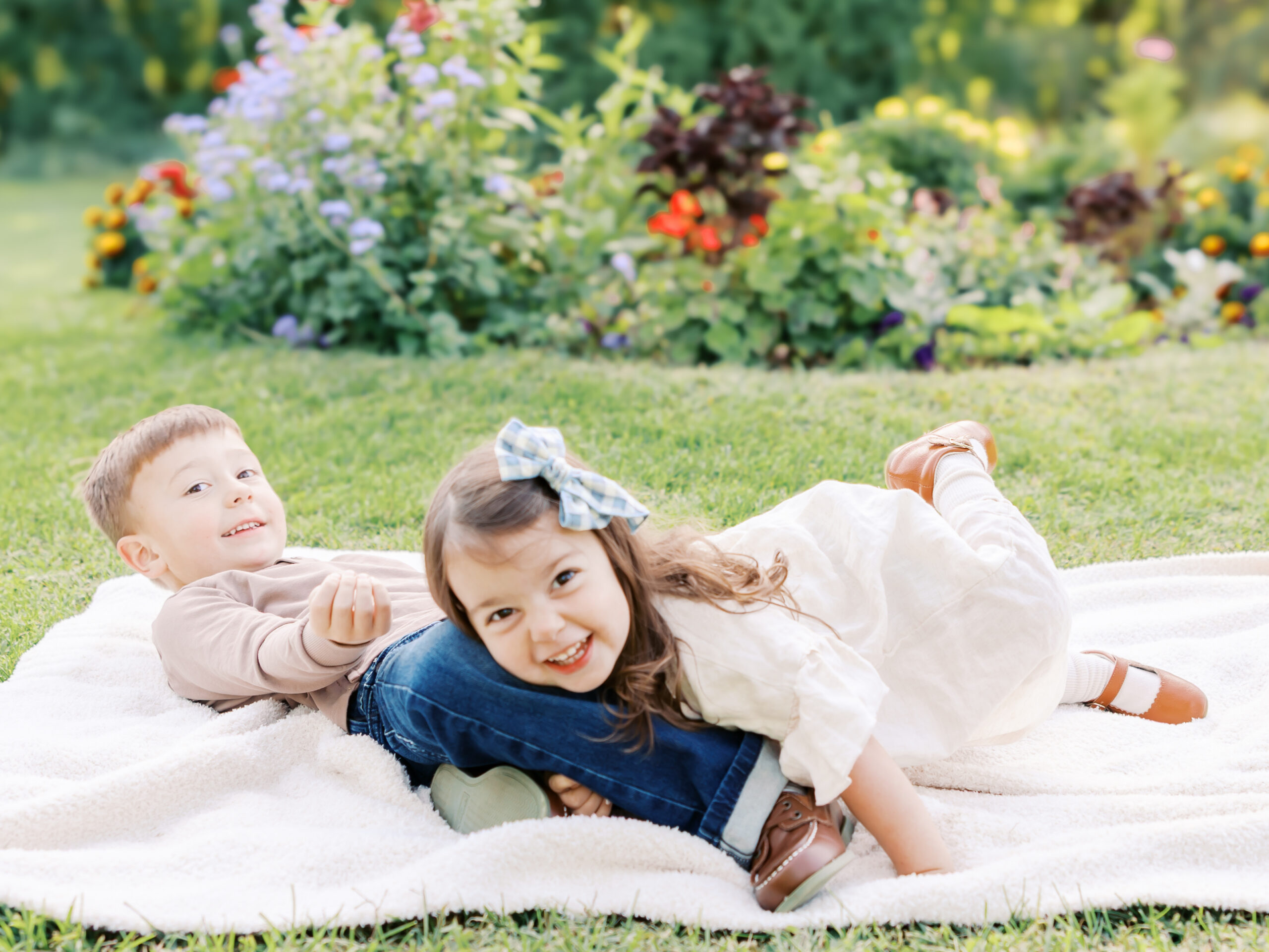 two siblings wrestle on a blanket at arneson acres park, edina, minnesota for their minneapolis family photography session with angela watts photography.