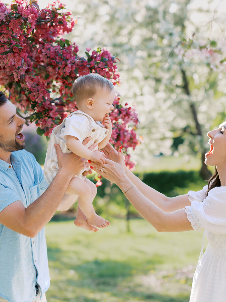 boy getting passed between two parents at lyndale park gardens during their minneapolis family photography session