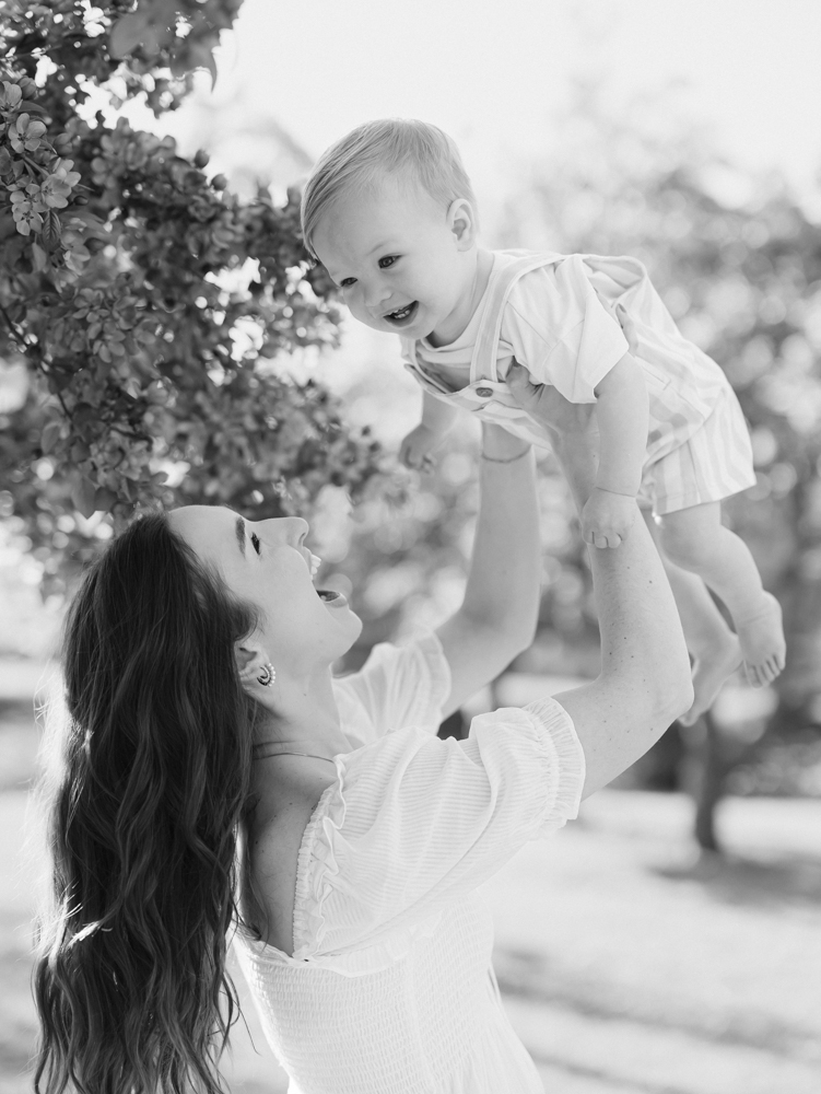 mom holds up baby boy during their minneapolis family photography session at lyndale park gardens